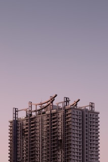 Modern high-end residential building facade with clean lines and glass balconies under soft lavender sky.