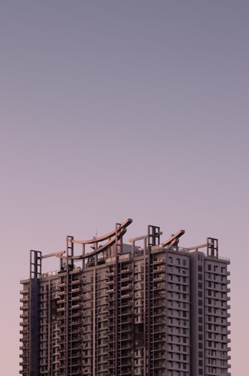 Modern high-end residential building facade with clean lines and glass balconies under soft lavender sky.