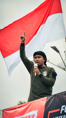 A confident leader speaking passionately at a podium with a national flag backdrop.