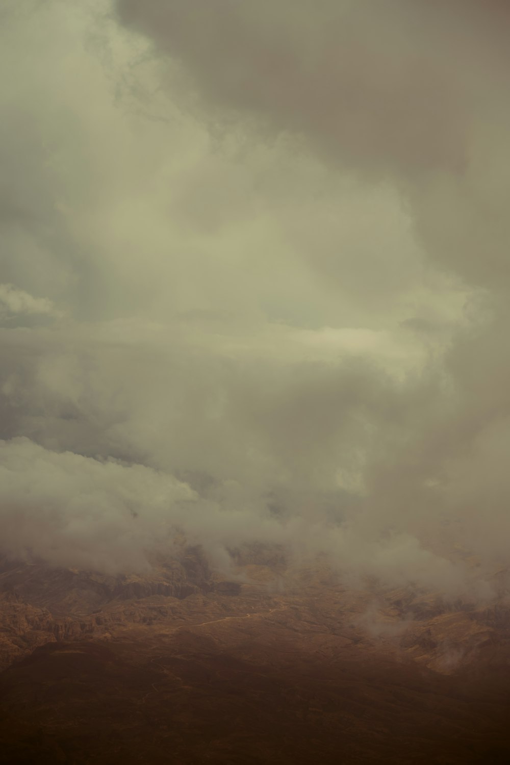 a plane flying through a cloudy sky with a mountain in the background