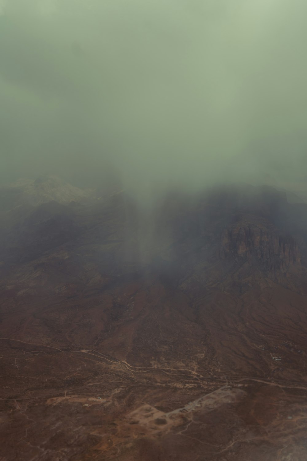 an airplane flying over a mountain covered in clouds