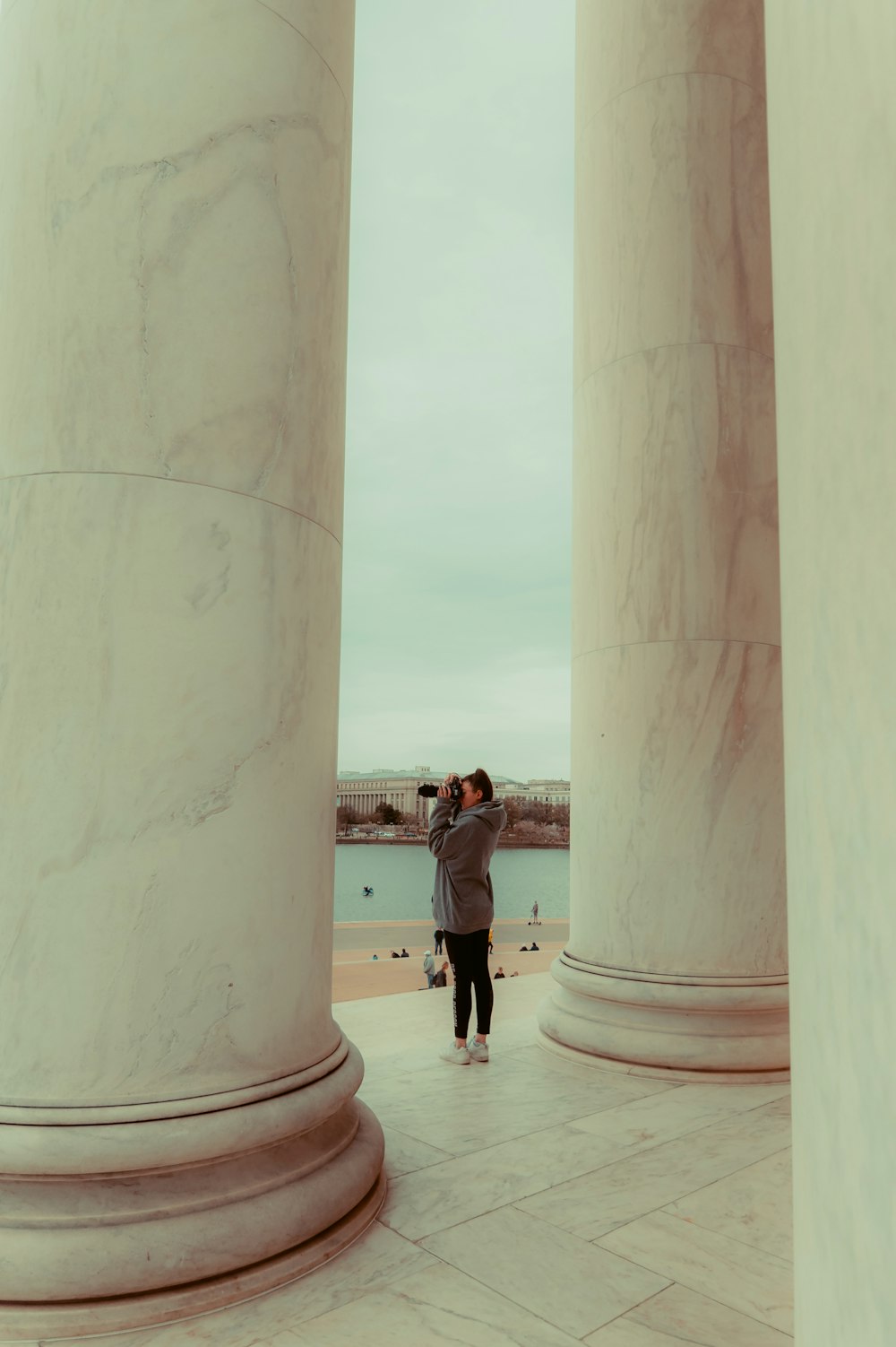 a man taking a picture of himself through the pillars of a building