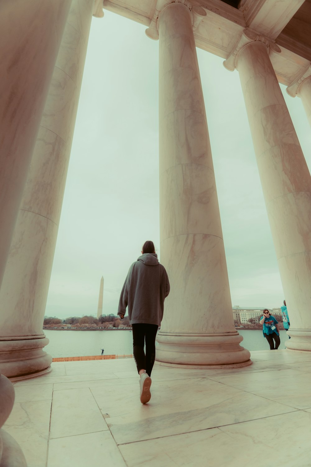 a person walking in front of a row of pillars