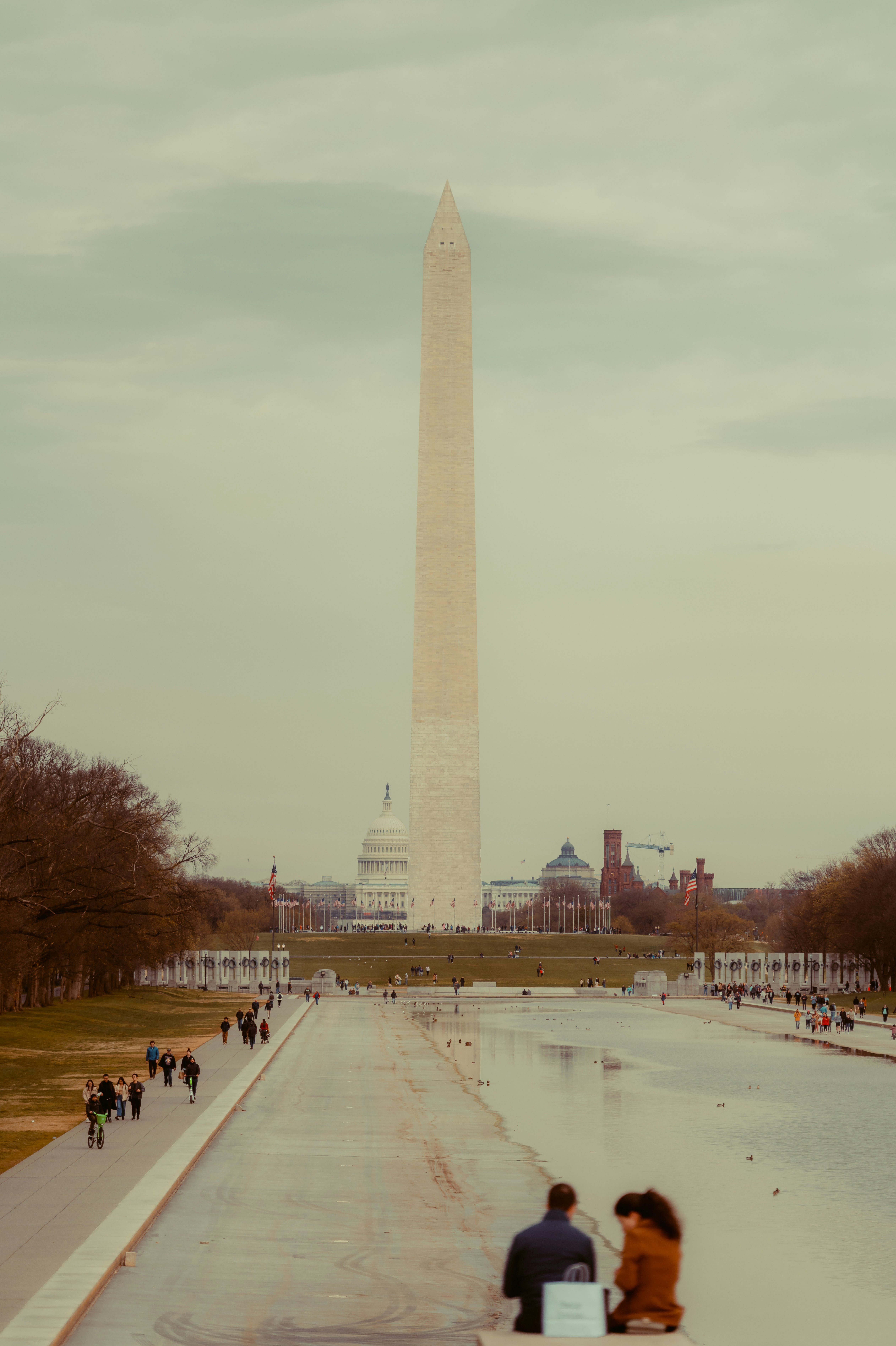 two people sitting on a bench in front of the washington monument