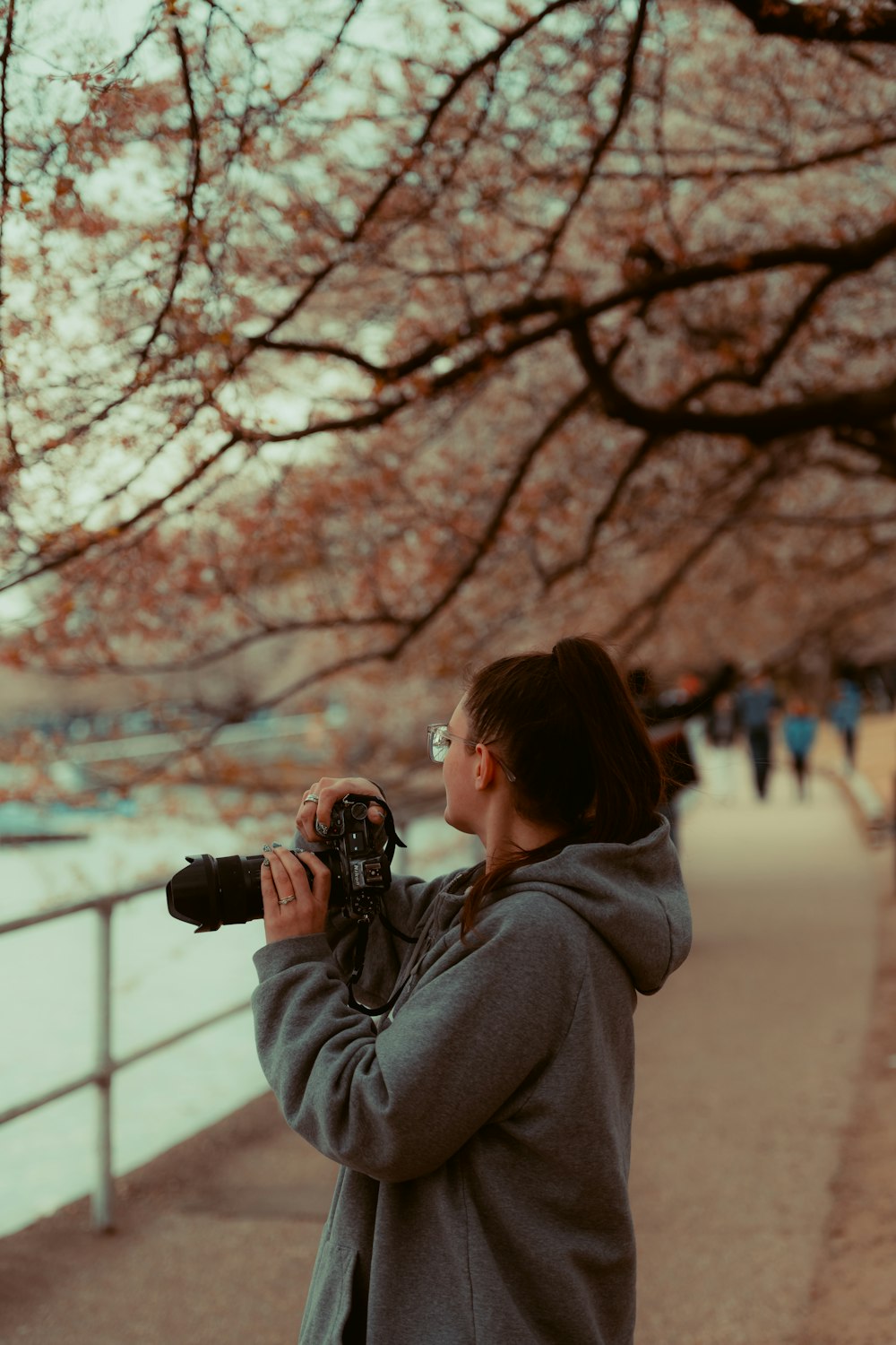 a woman taking a picture of a tree with a camera