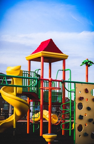 Kids sliding down a vibrant slide attached to a fun jungle gym