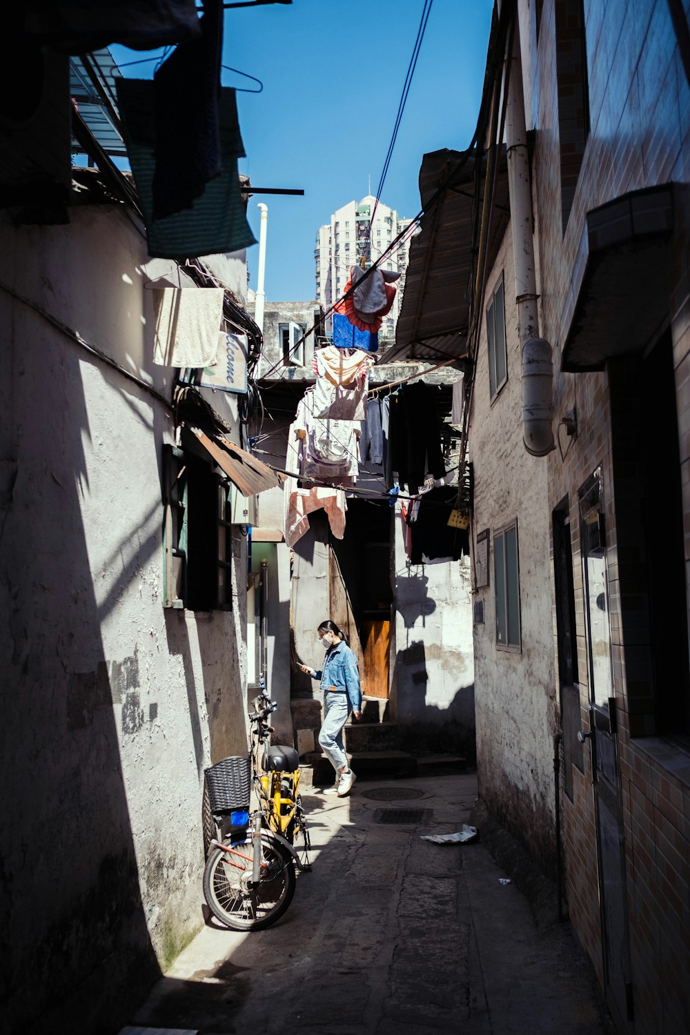 a narrow alleyway with a man hanging out of the window