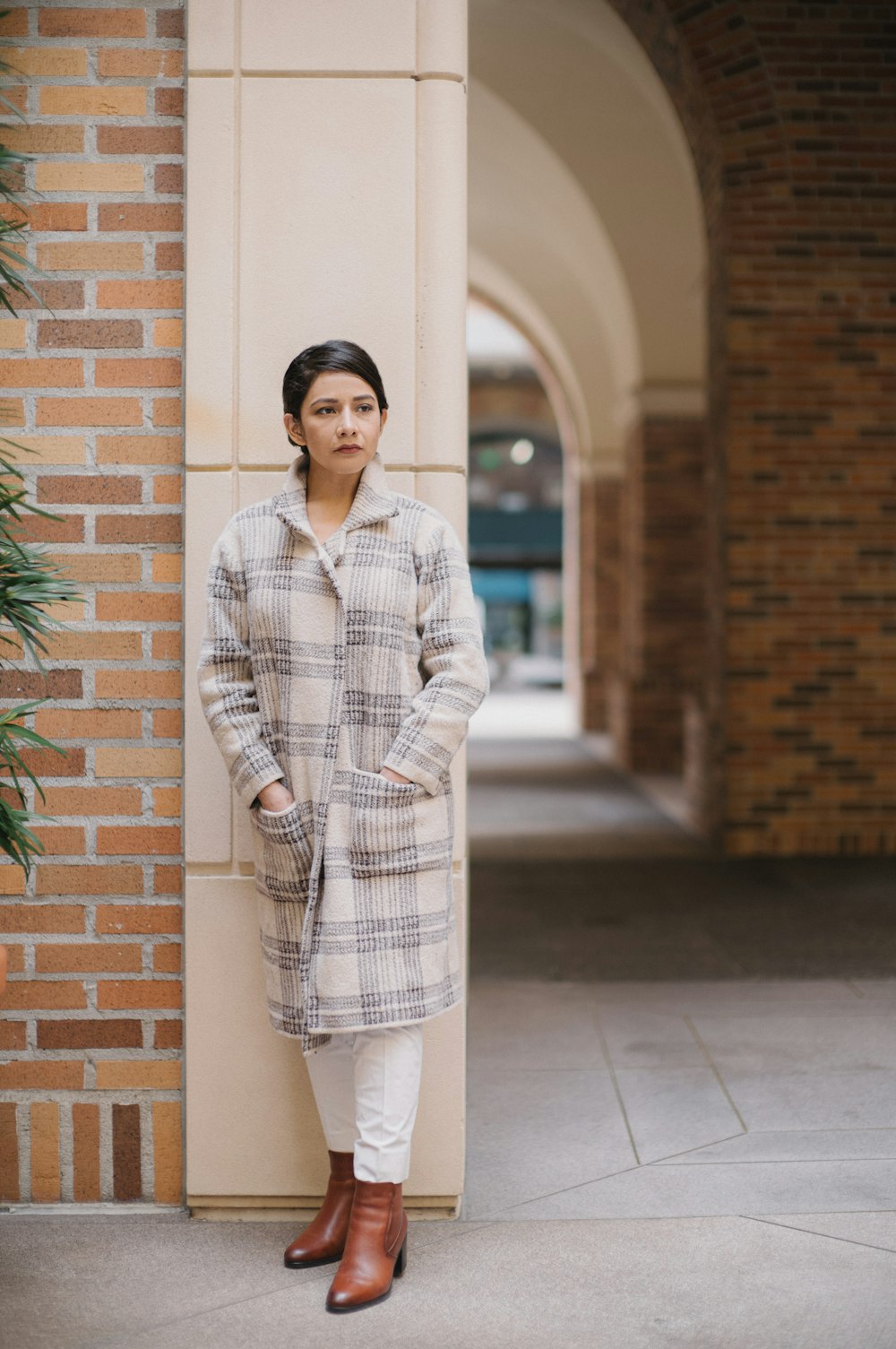 a woman standing next to a brick wall