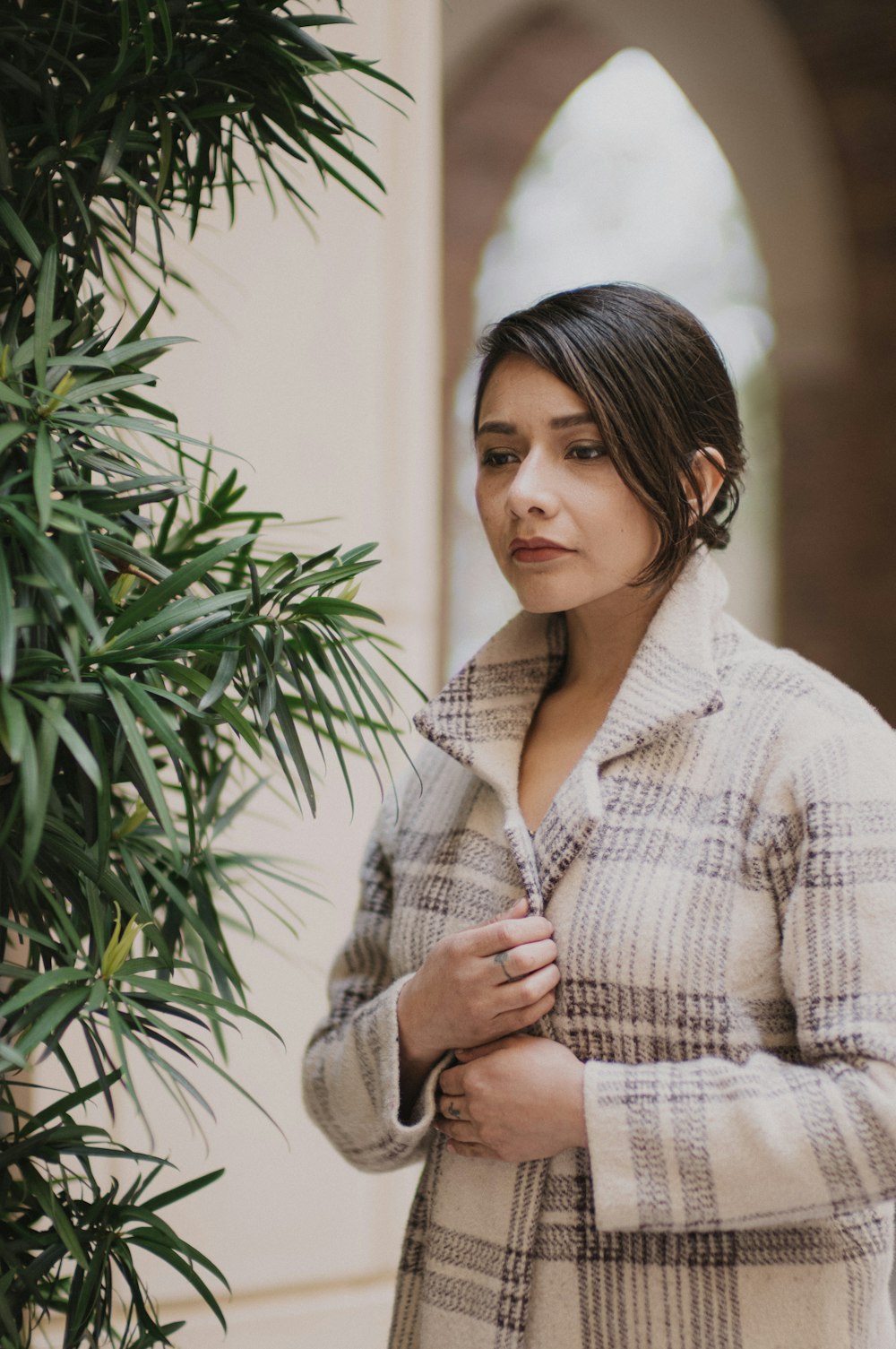 a woman standing next to a tree wearing a coat