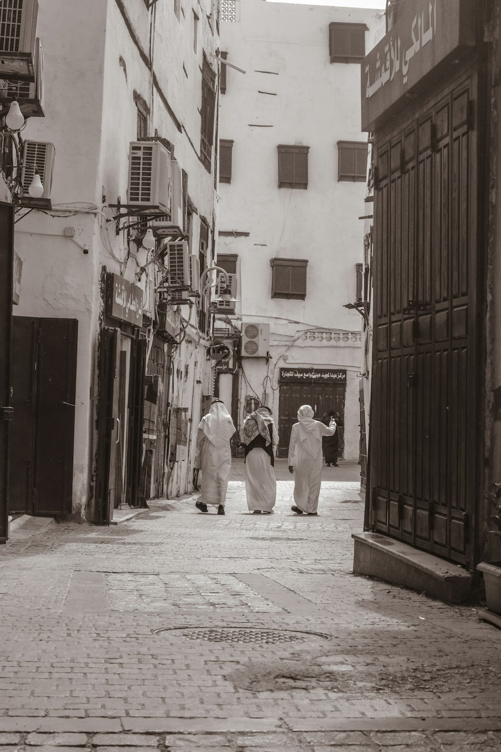 a group of people walking down a street next to tall buildings