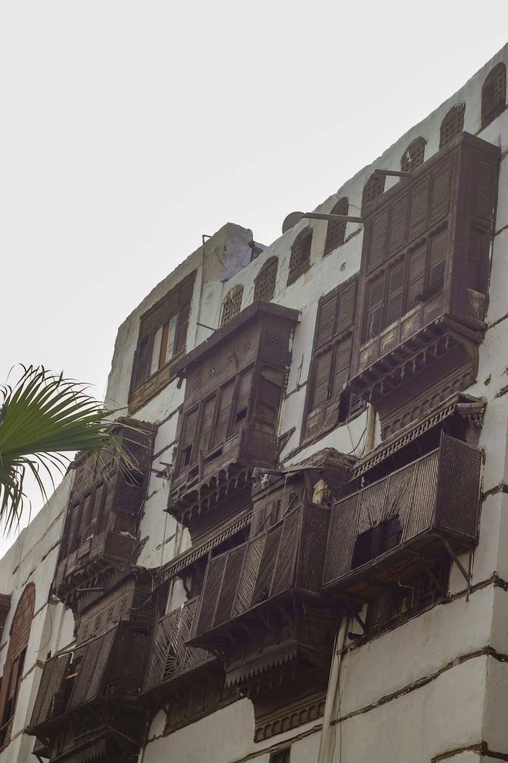 an old building with balconies and a palm tree