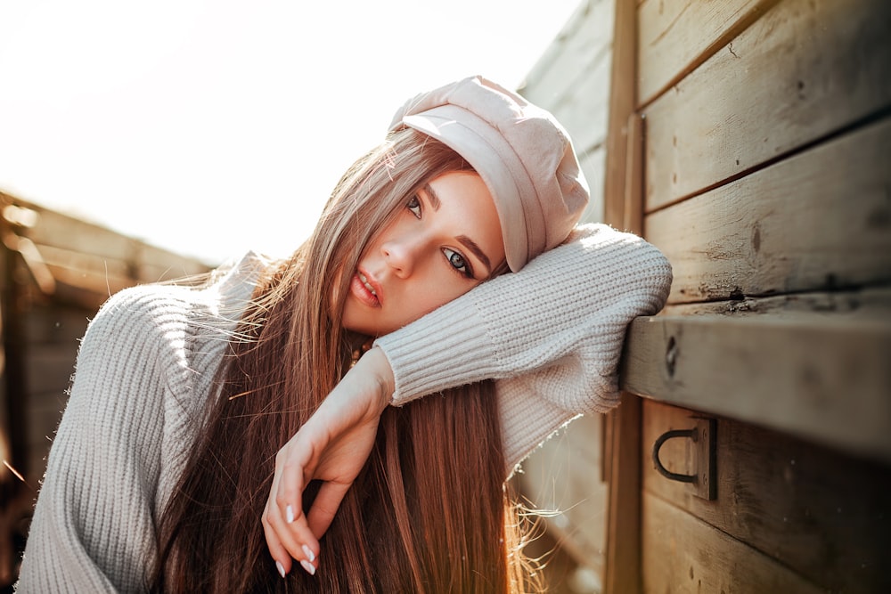 a beautiful young woman leaning against a wooden wall