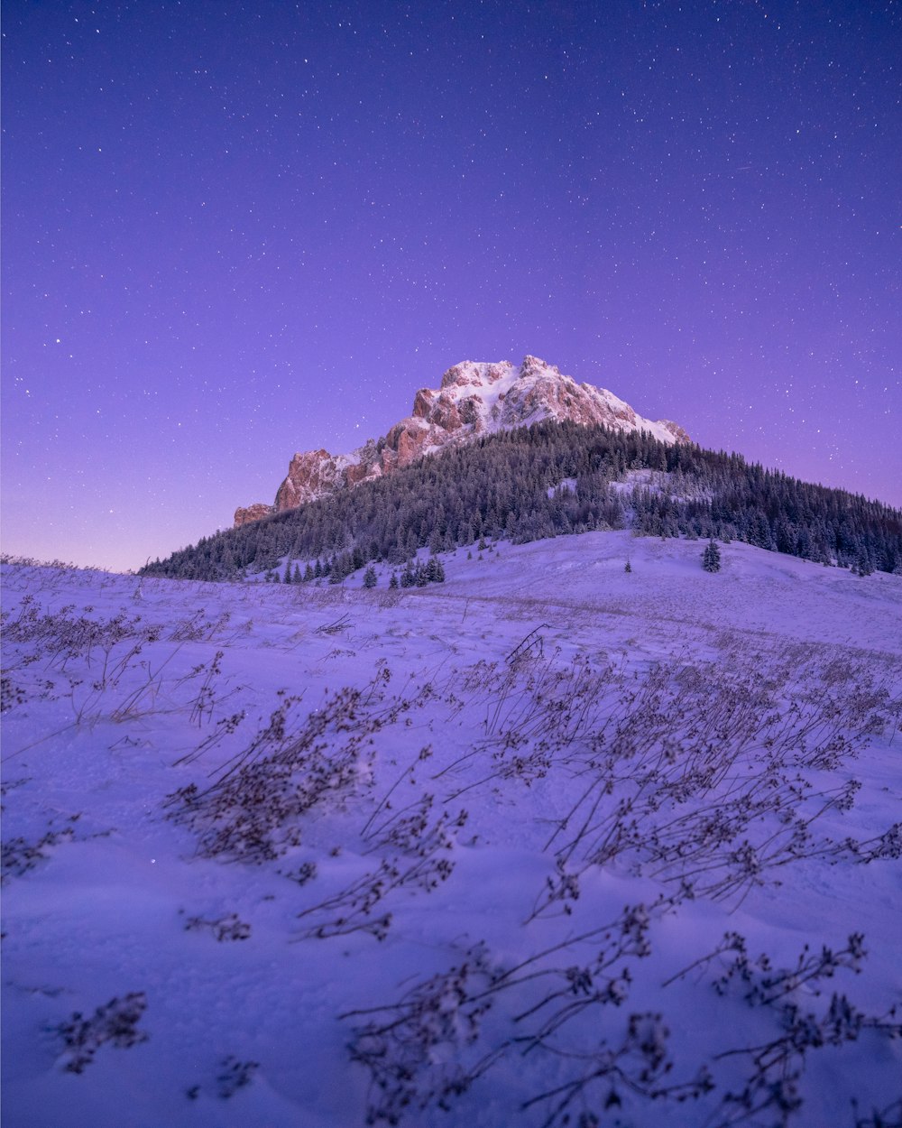a snow covered mountain under a purple sky