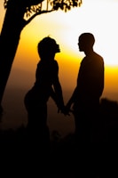 Sunset silhouette of the couple holding hands in a garden.