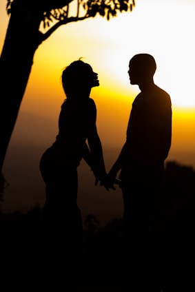 A warm sunset over a rural African village with a couple holding hands, symbolizing enduring love.