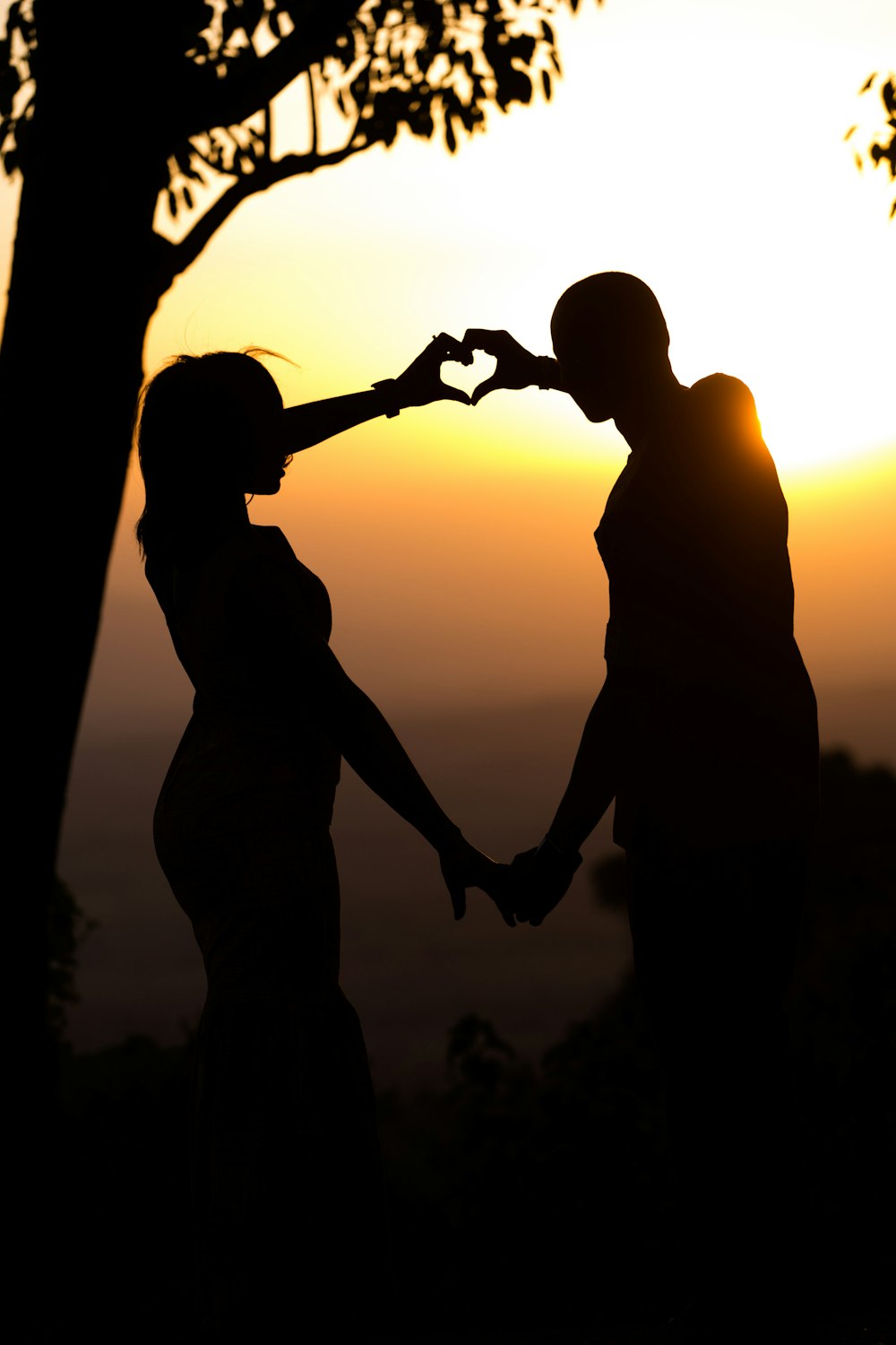 a man and a woman holding hands in front of a sunset