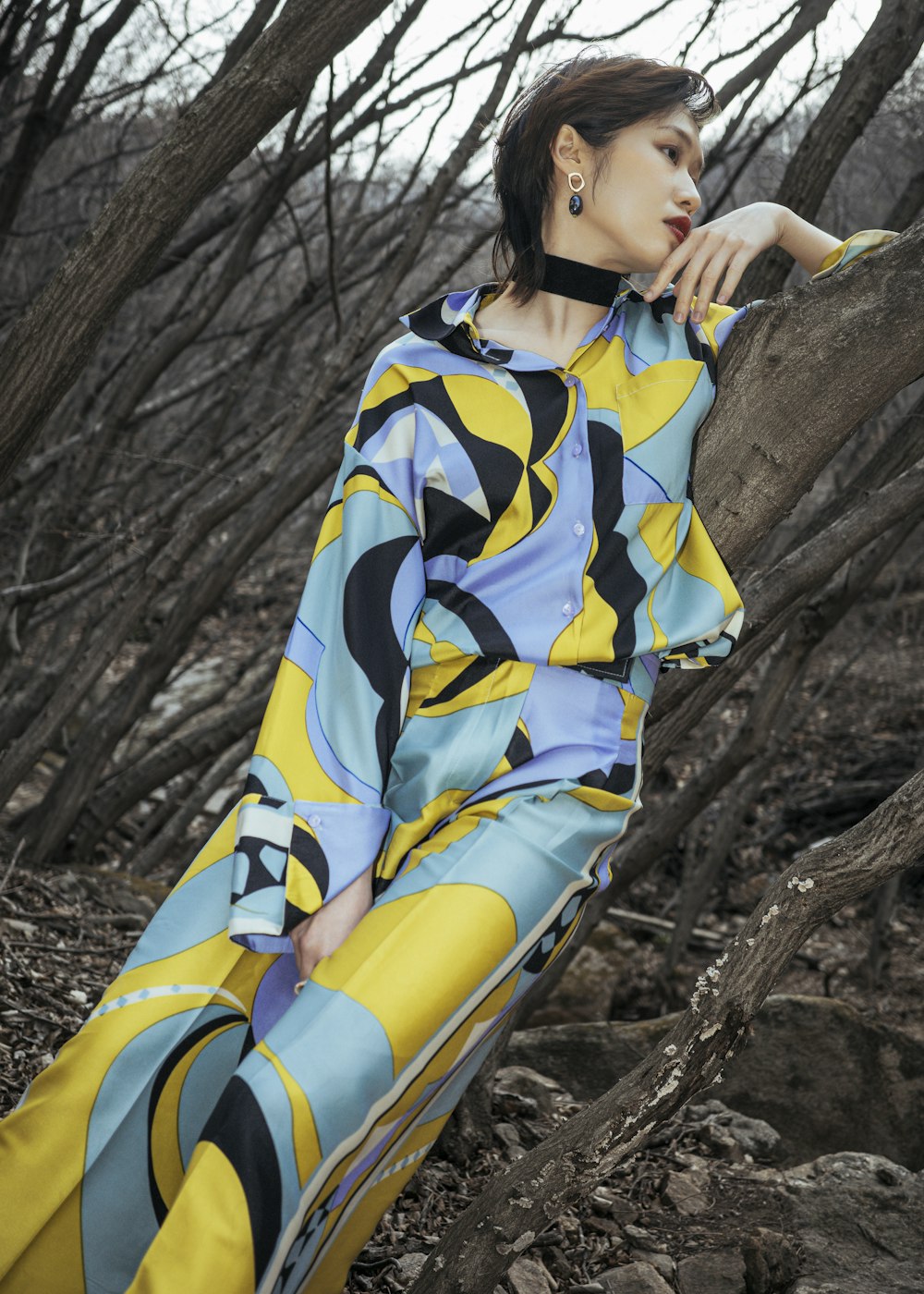 a woman sitting on a tree trunk in a colorful dress
