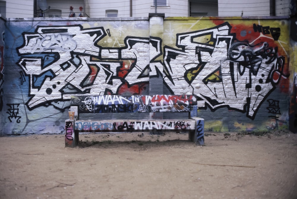 a bench in front of a graffiti covered wall