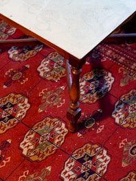 Round glass top coffee table with wooden legs on a soft rug