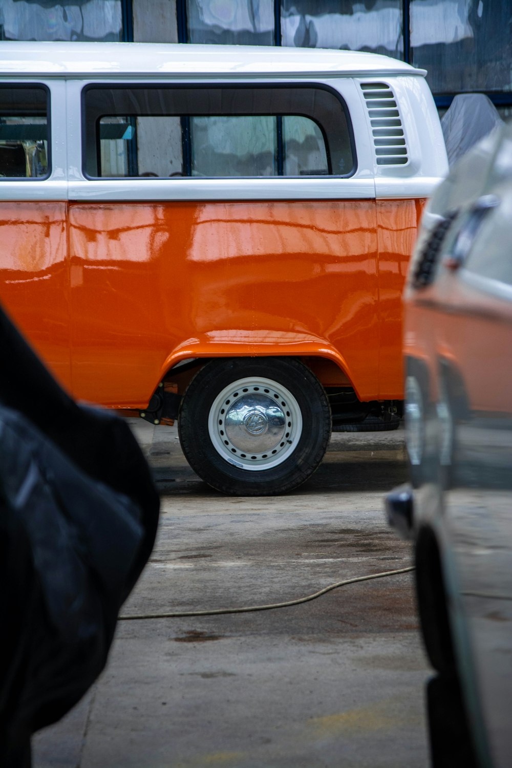 an orange and white vw bus parked in a parking lot