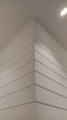 A craftsman carefully smoothing a wall in a modern interior under warm lighting.