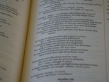 A close-up of an open book with printed text, focusing on several paragraphs organized by numbers and verses. The page appears to be from a religious or spiritual book.