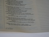 A close-up view of a page from a book, focusing on a passage that appears to be religious or spiritual text. The text is formatted in a structured, verse-like manner, with some lines in italics and numbers indicating sections or verses.