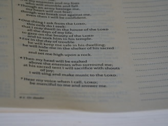 A close-up view of a page from a book, focusing on a passage that appears to be religious or spiritual text. The text is formatted in a structured, verse-like manner, with some lines in italics and numbers indicating sections or verses.