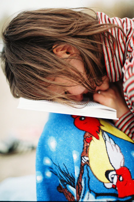 a girl with her head on a book