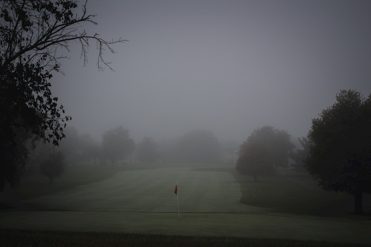 Foggy golf course with flag on a misty morning, the kind of wet weather that demands a waterproof jacket