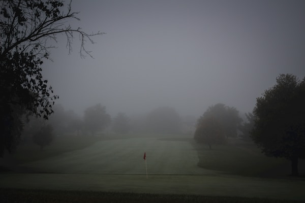 Foggy golf course with flag on a misty morning, the kind of wet weather that demands a waterproof jacket