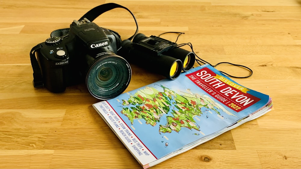 a camera sitting on top of a wooden floor next to a book