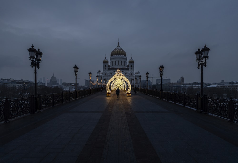 a walkway with a lit archway leading to a building