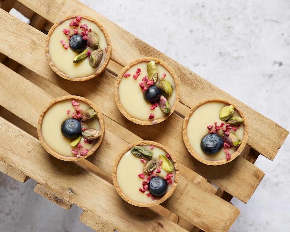 four desserts are arranged on a wooden tray