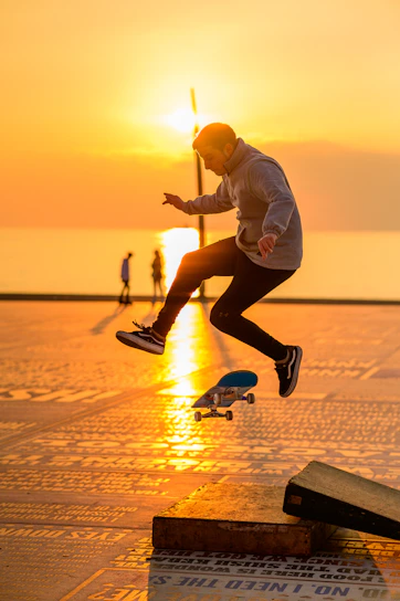 Skateboarder mid-air against a sunset over Baja California coastline.