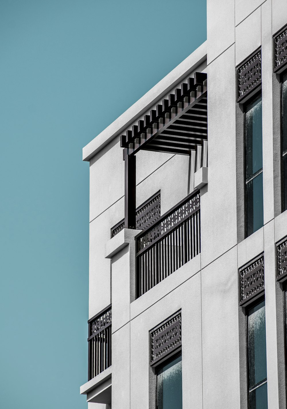 a tall white building with balconies and a sky background