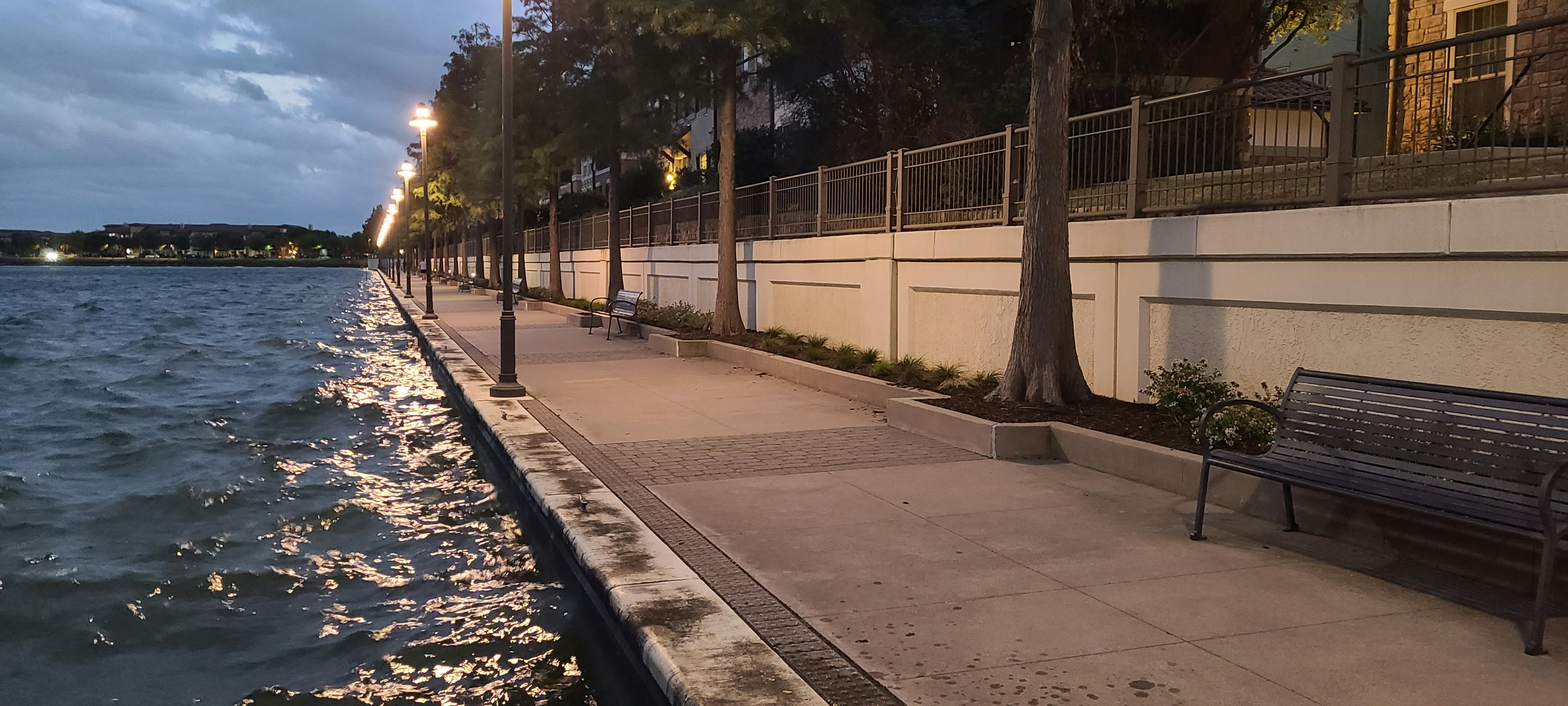 a bench sitting on the side of a road next to a body of water