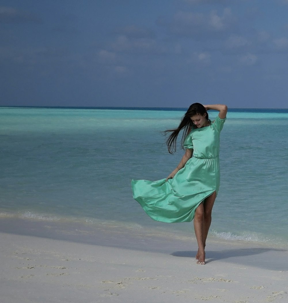 a woman in a green dress standing on a beach