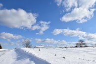 a road that is covered in snow under a cloudy blue sky