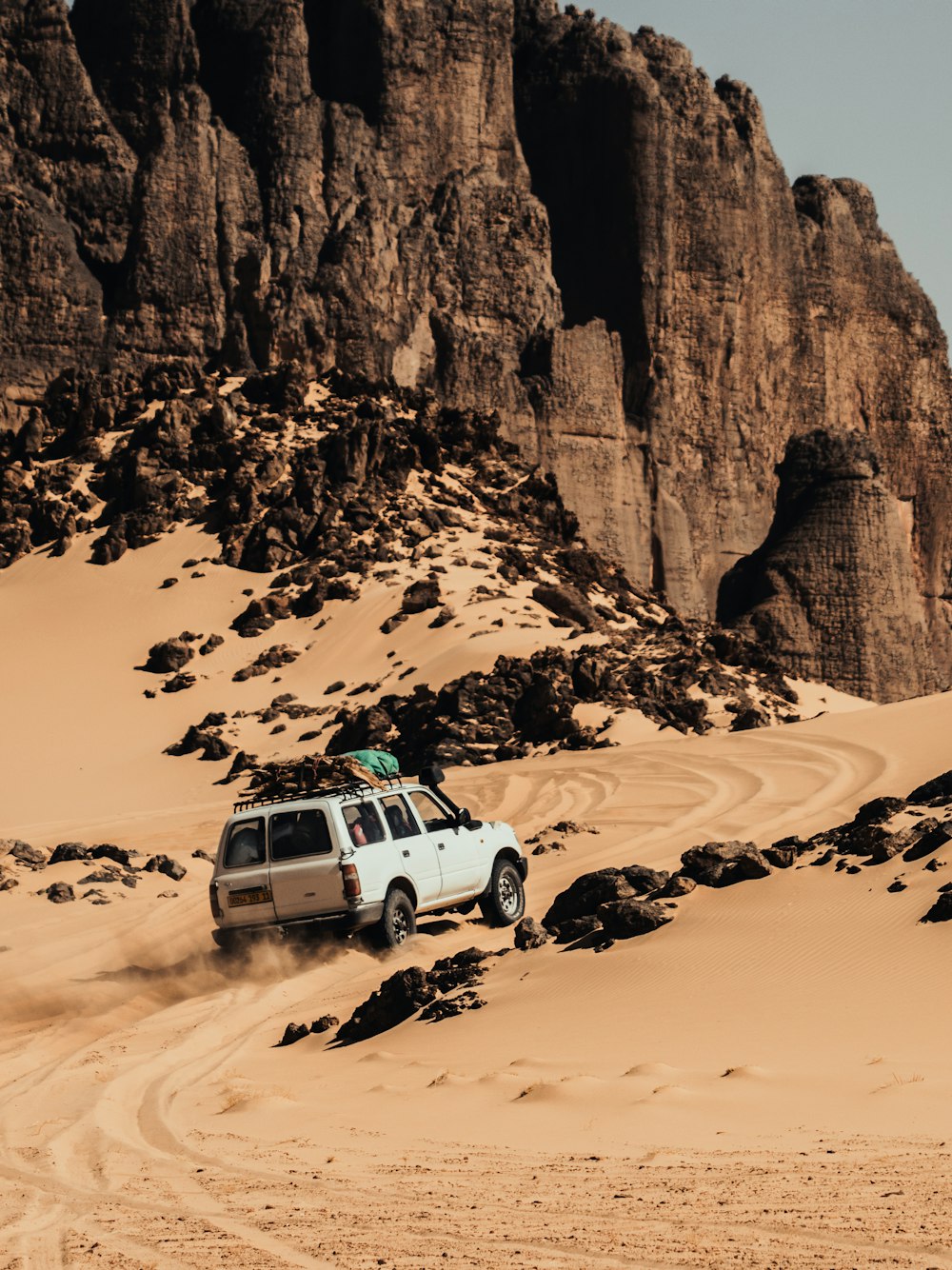 a car driving through the desert with a mountain in the background