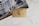 A gold American Express business credit card is placed on top of an advertisement featuring people in a professional setting. The surface is a white marble or similar texture. The card includes various numbers and text, with the notable American Express logo.