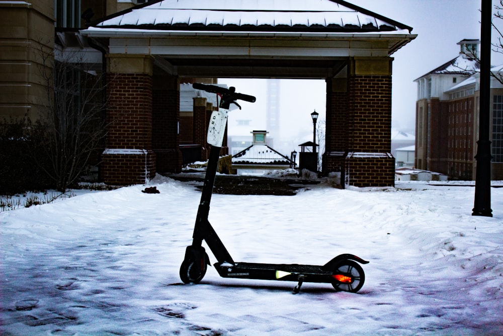 a scooter parked in the snow in front of a building