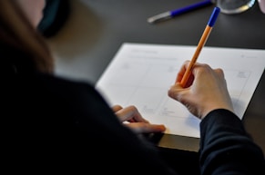 Close-up of hands writing a personalized fitness plan on sleek black paper with neon green accents.