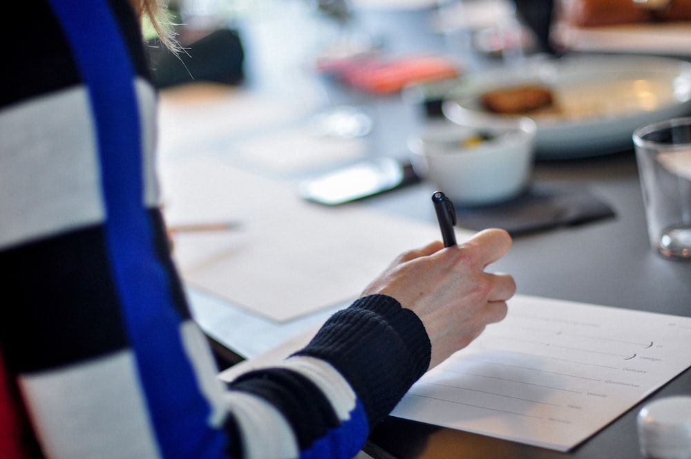 a person sitting at a table writing on a piece of paper