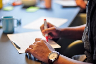 a person sitting at a table writing on a piece of paper