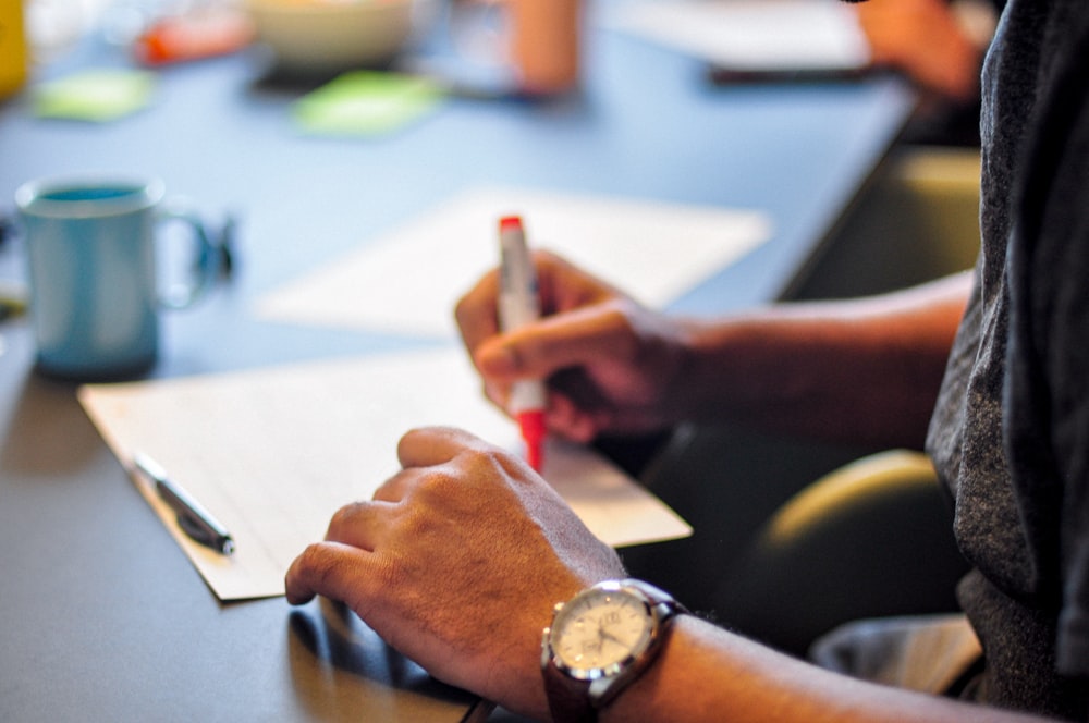 a person sitting at a table writing on a piece of paper