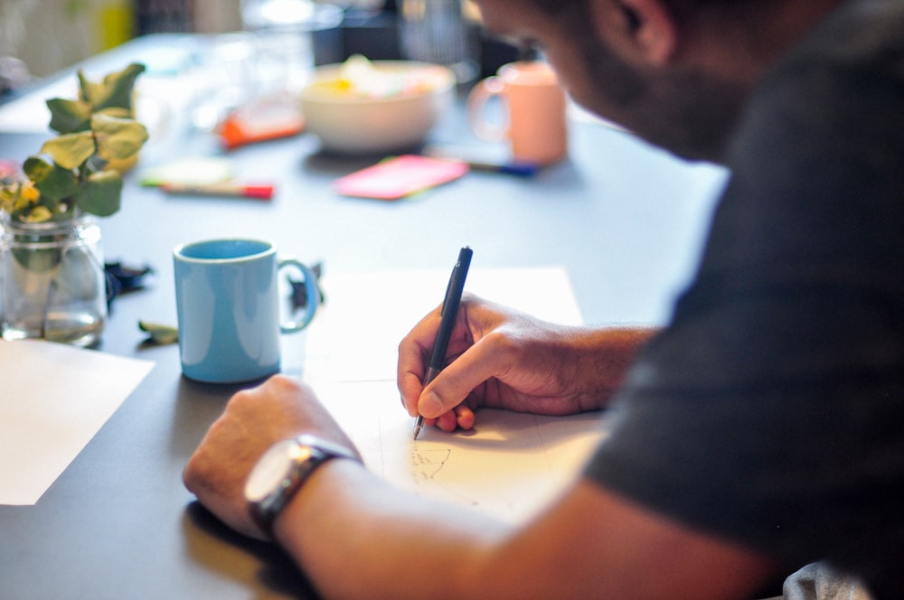 a man sitting at a table writing on a piece of paper