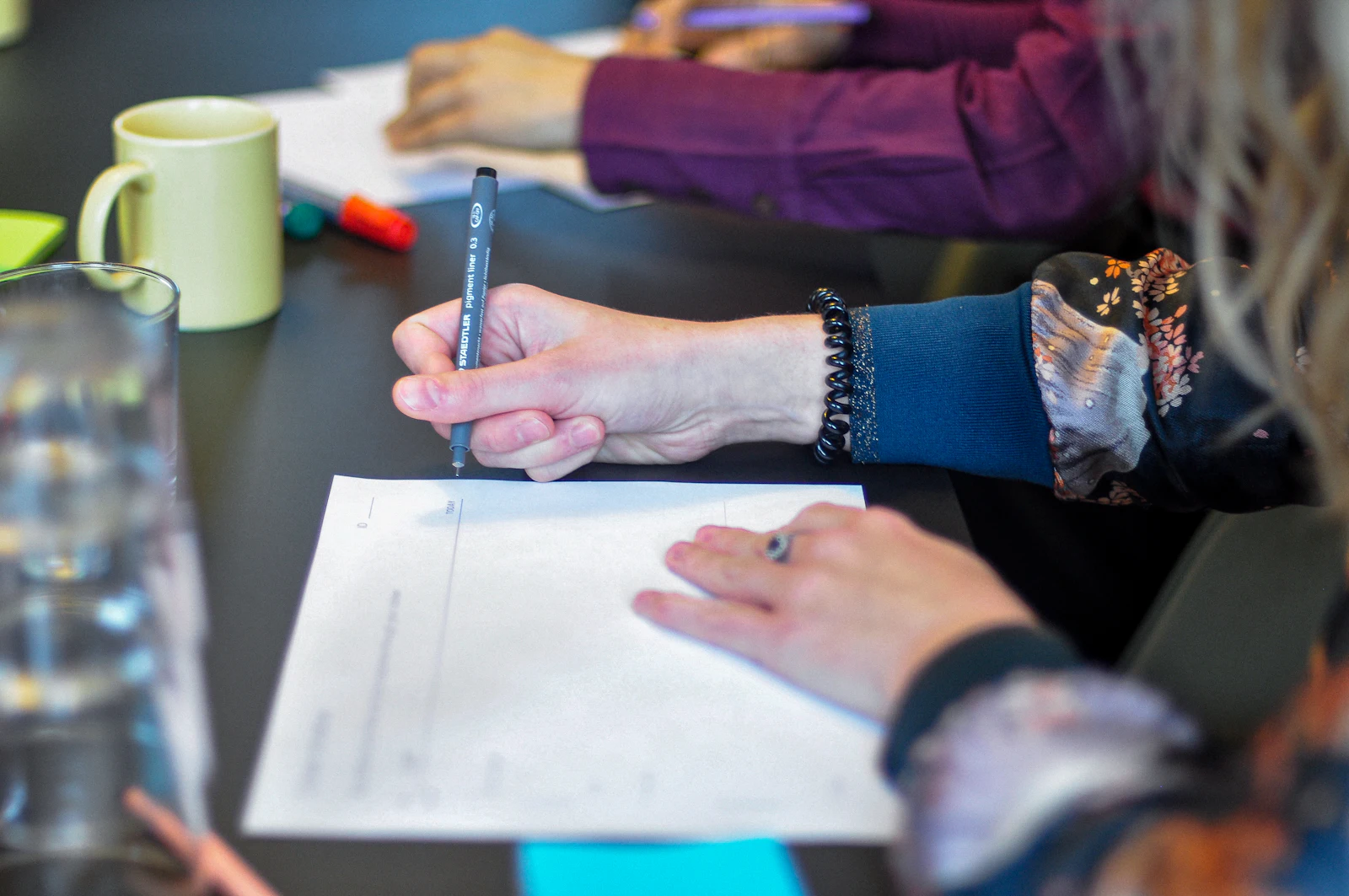 People gathered around a table writing and working through material together