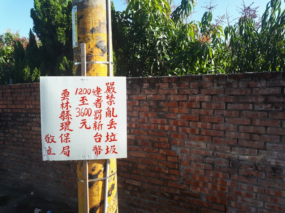 a sign on a pole in front of a brick wall