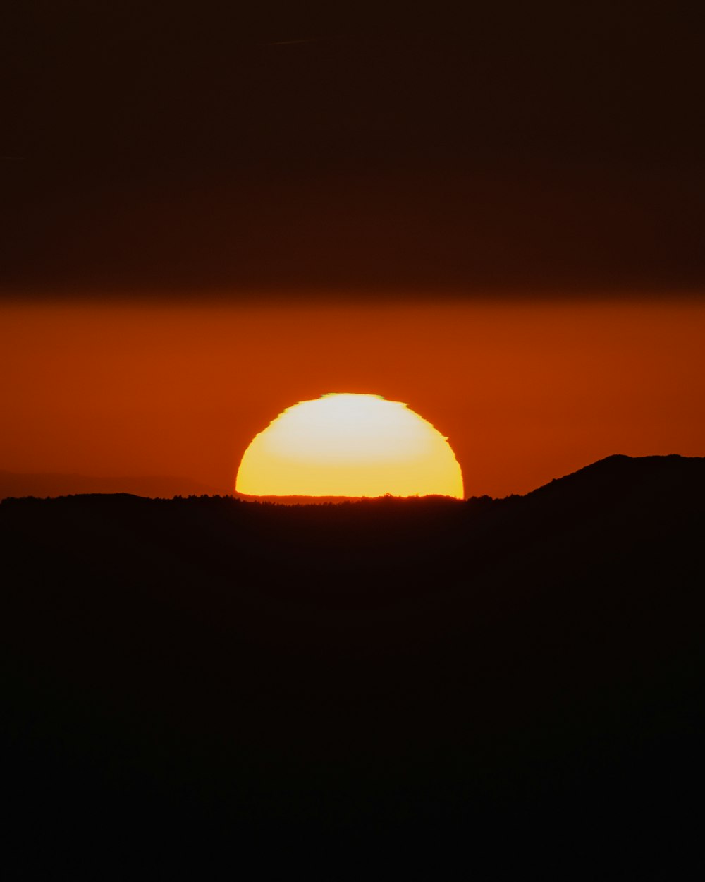 the sun is setting over a mountain range